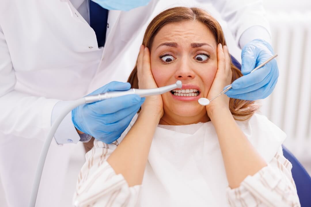 Woman sitting at the dental chair afraid of dental tools